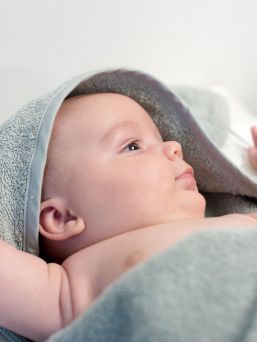 Light-colored hooded towel for babies to shower and bath tubs moments.