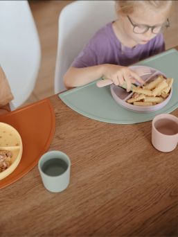 Mushie silicone place mat. The place mat stays firmly on the table and keeps the dishes and mess in one place.