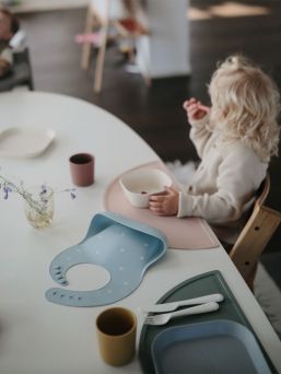 Mushie silicone place mat. The place mat stays firmly on the table and keeps the dishes and mess in one place.