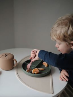 Mushie silicone place mat. The place mat stays firmly on the table and keeps the dishes and mess in one place.