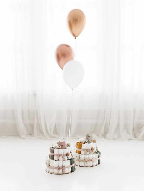 A light-colored diaper cake is a beautiful, modern and necessary gift to take to babyshows, for example, or to remember a coworker.